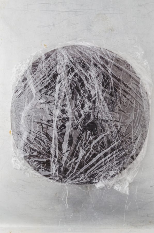 a chocolate cake layer wrapped in plastic wrap ready to go in the freezer