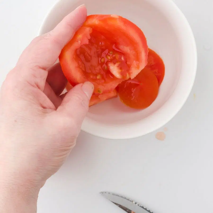 a woman holding a deseeded tomato - illustrating how easy it is to deseed a tomato