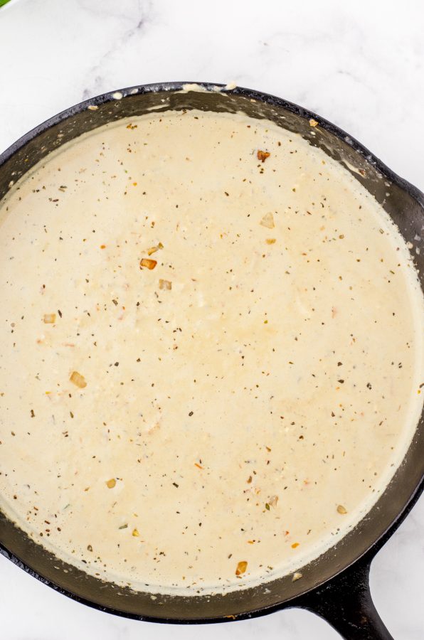 Creamy sauce for chicken florentine in a cast iron skillet.