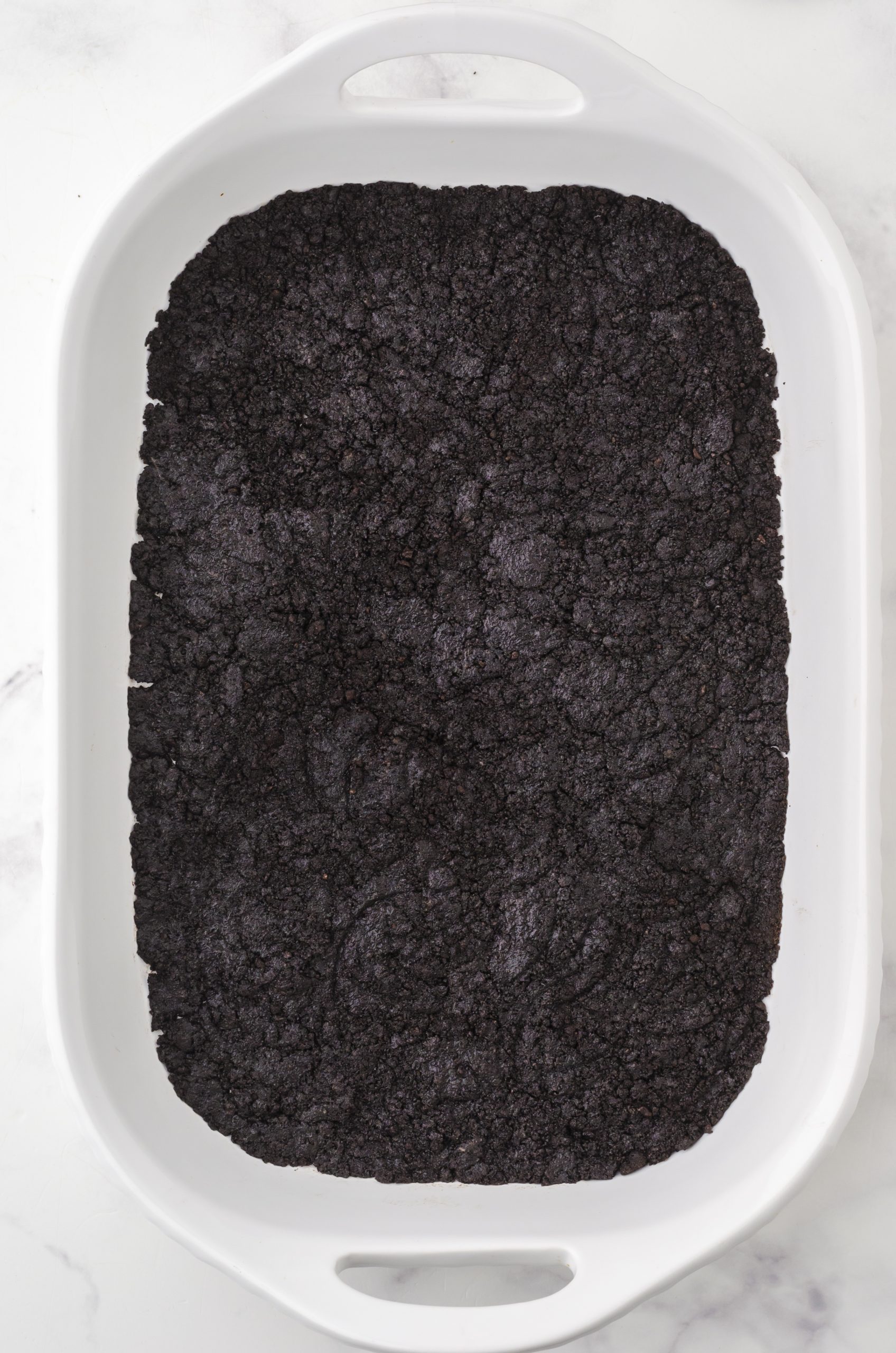 the oreo crust for oreo ice cream cake pressed into a 9 x 13 inch pan.