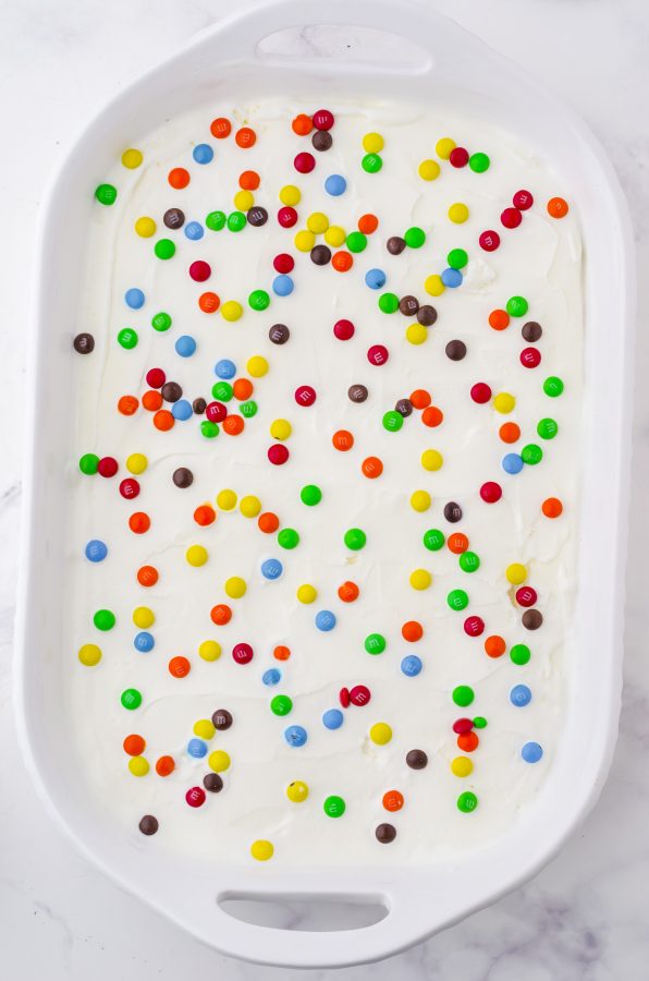 mini m&ms sprinkled over the ice cream layer of an oreo ice cream cake