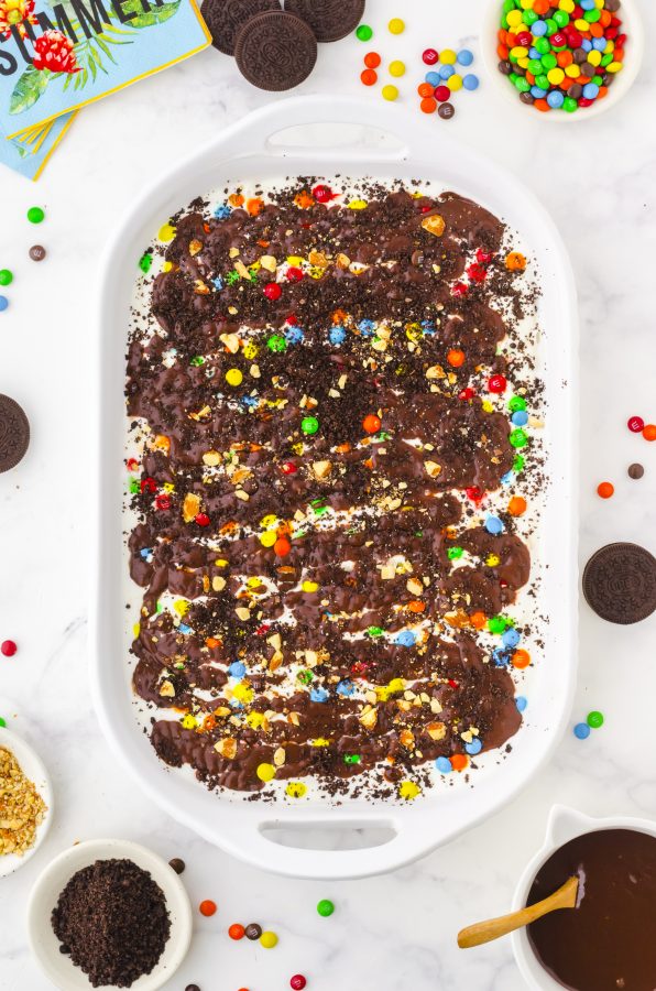oreo crust ice cream cake in that has oreo crumbs and m&ms sprinkled on the top in a 9 x 13 inch pan