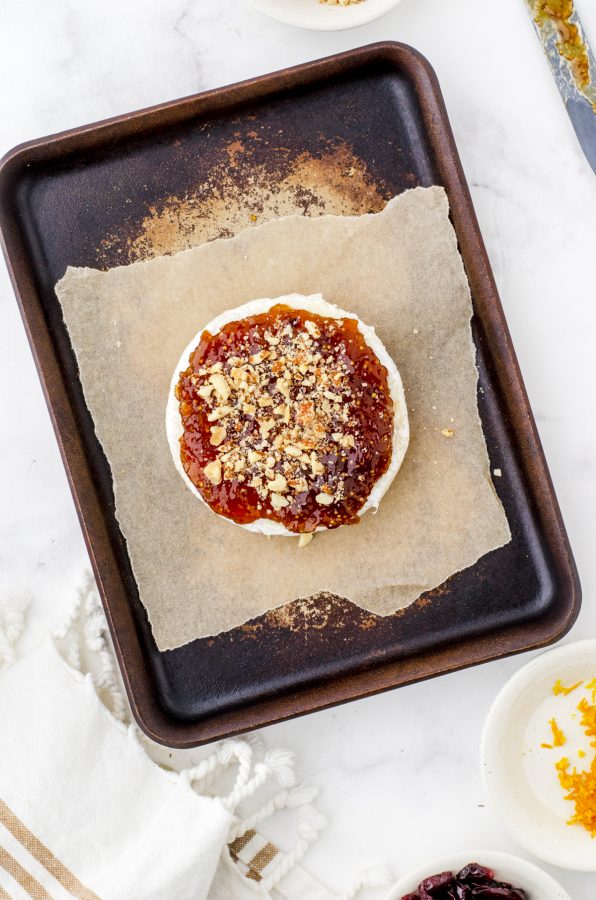 round of brie cheese with fig jam and nuts sprinkled on it
