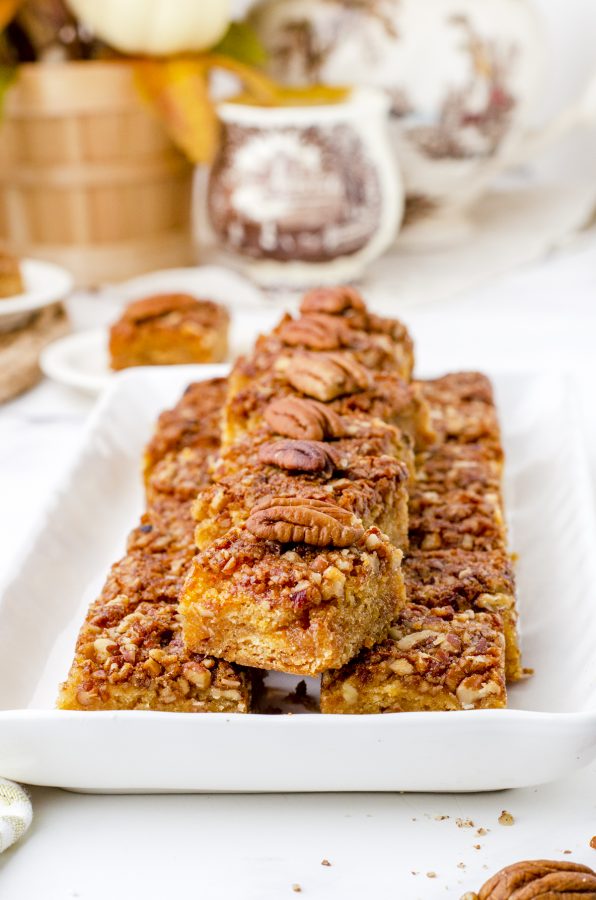 a platter of pecan pie bars stacked with pecan slices lining the tops.
