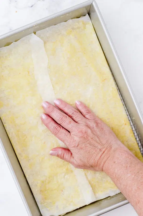 pressing the becan pie bar crust into the bottom of a baking pan