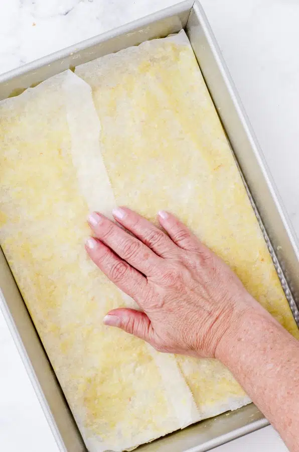 pressing the pecan pie bar crust into the bottom of a baking pan