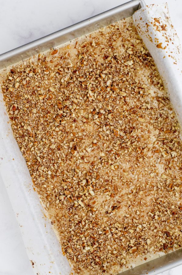 Chopped pecans sprinkled on the top of pecan pie bar filling.
