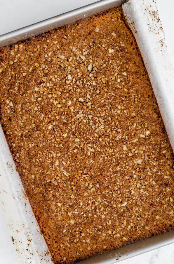 Baked pecan pie bars in a parchment lined pan.