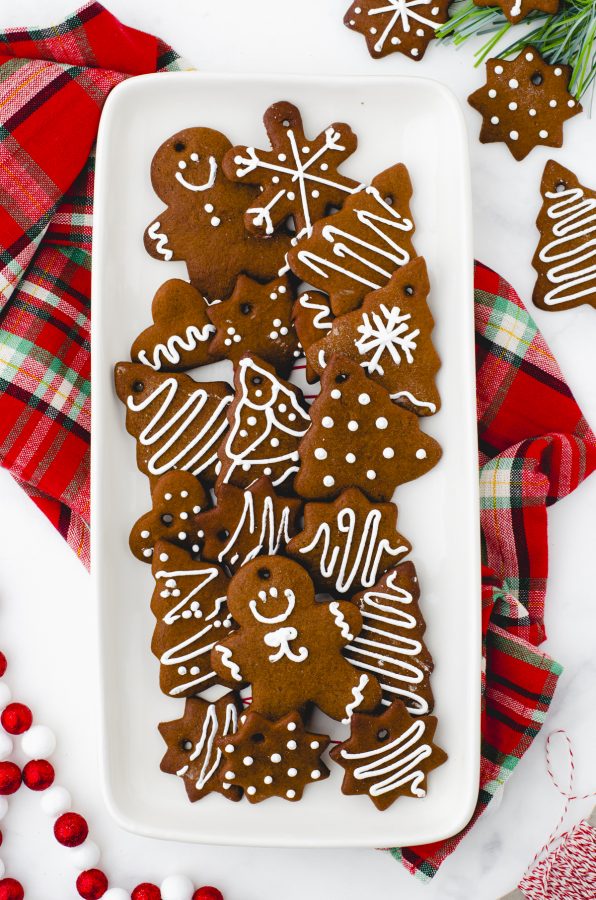 An assortment of different shaped gingerbread cookies - stars, trees, gingerbread men, and hearts - on a white platter.