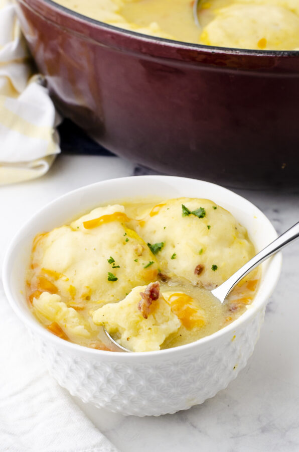 A bowl of potato soup with drop dumplings on the top.