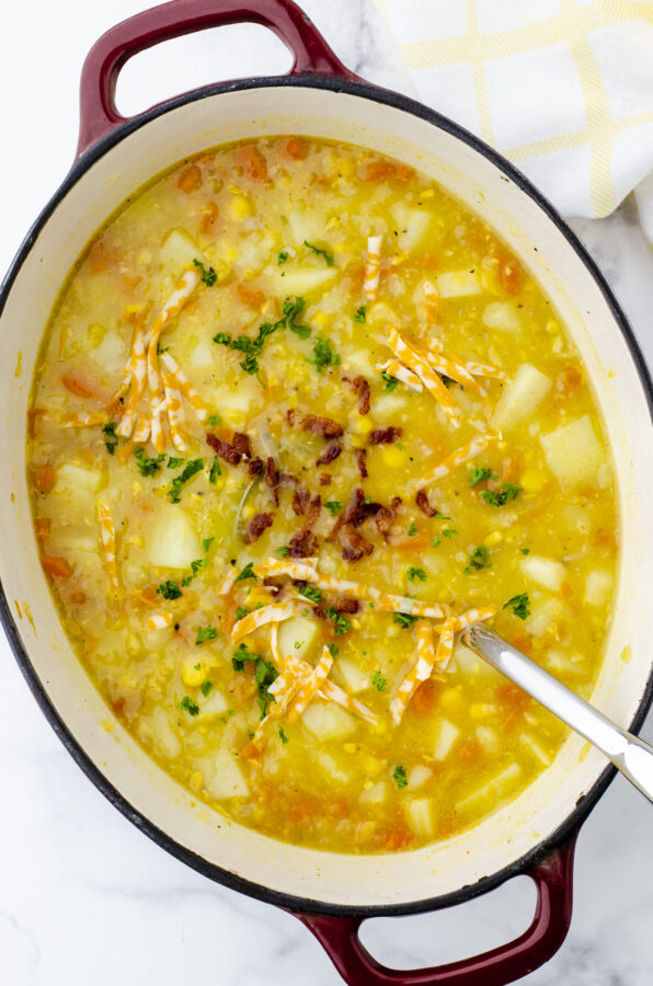 A pot of easy potato soup with chunky potatoes, corn, bacon bits, and shredded cheese.