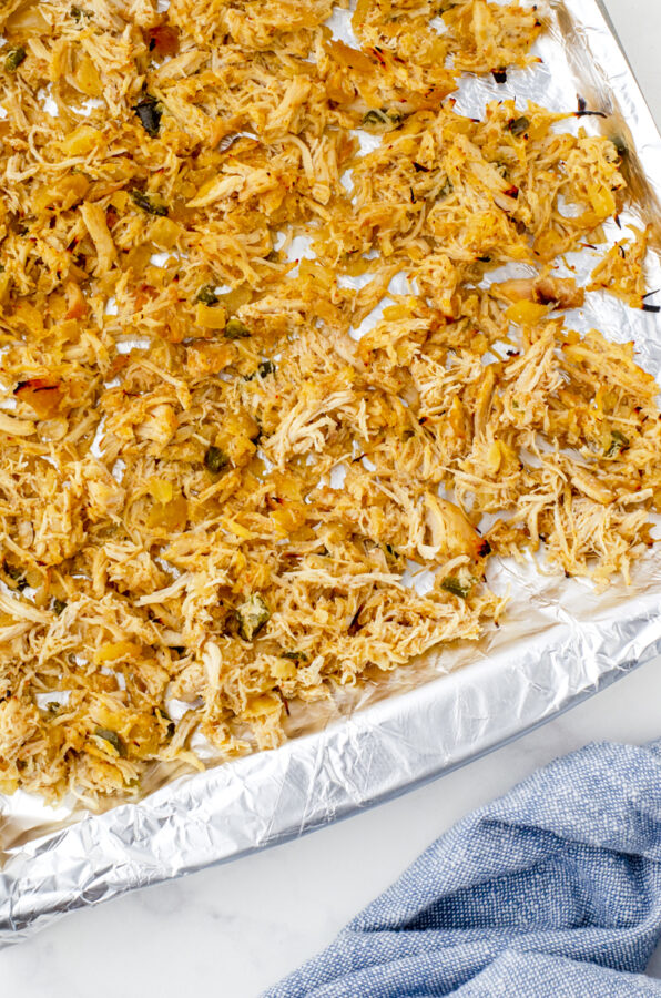 close up of shredded chicken after it has been under the broiler and is lightly charred on the edges.