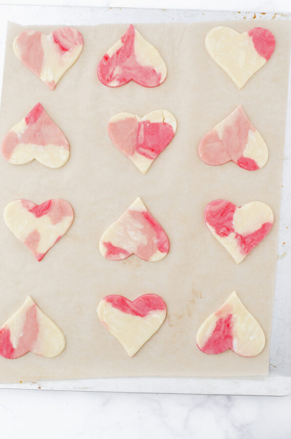 Heart cookies in marble sugar cookie dough on a baking sheet.