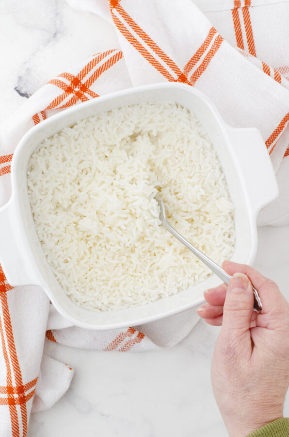 A person fluffing oven baked rice with a fork