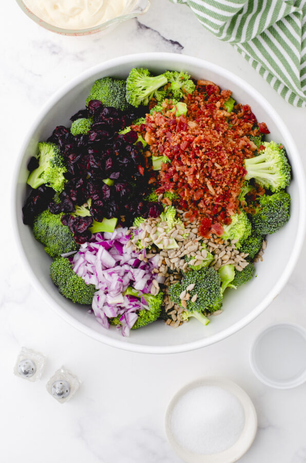 a big bowl with all the ingredients for broccoli salad in it ready to be stirred together.