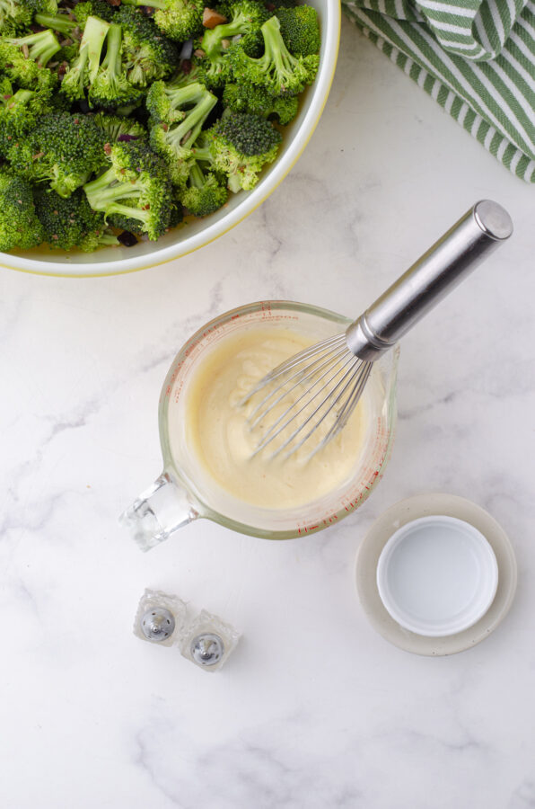 The miracle whip dressing being whisked in a bowl for broccoli salad with cranberries