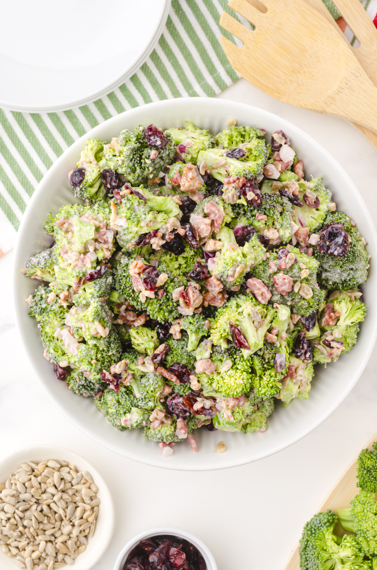 Brocolli salad in a white bowl with cranberries and bacon bits with a creamy dressing