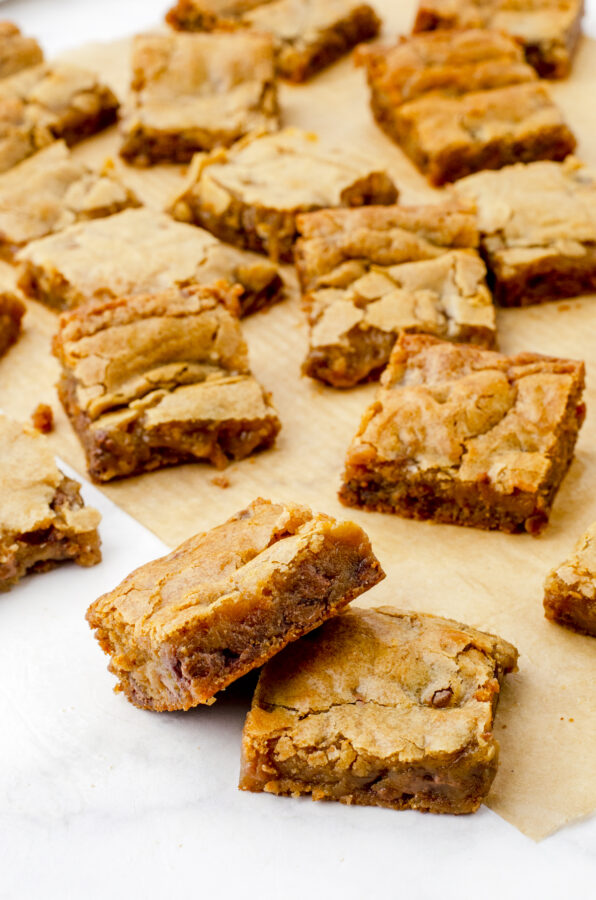 chewy butterscotch brownie blondies stacked up and other squares of brownies behind