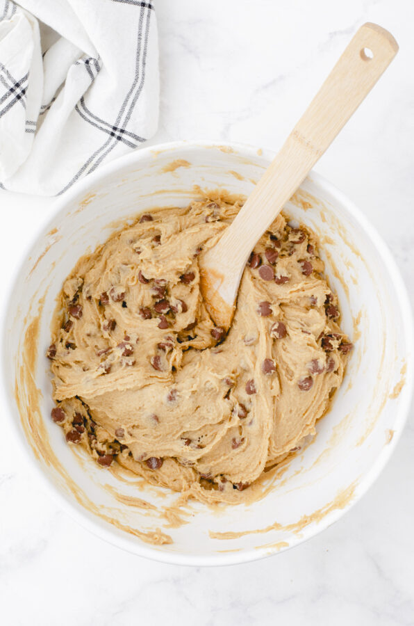 butterscotch brownie batter in a large mixing bowl after chocolate chips have been stirred in with a wooden spoon