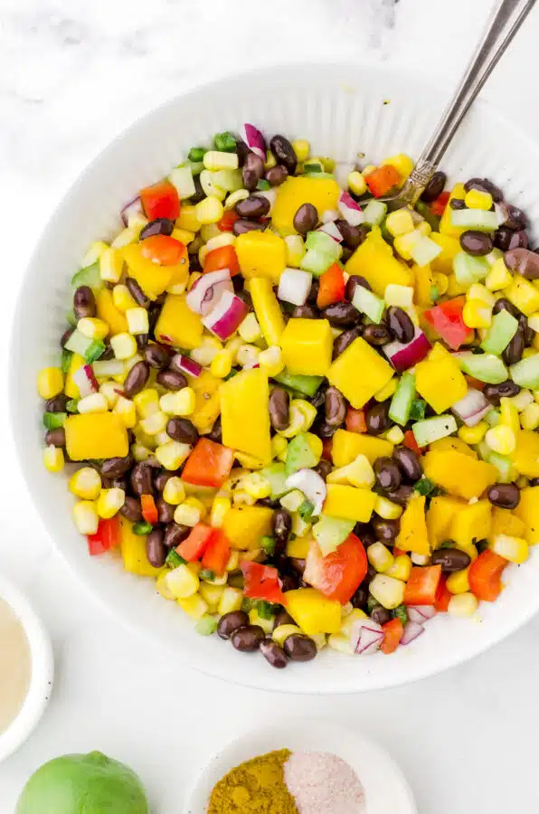 Mango salad ingredients stirred together in a bowl.