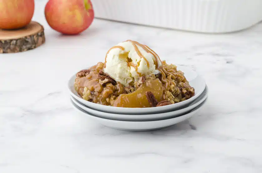 apple crisp with apple pie filling on a plate with ice cream and caramel drizzle