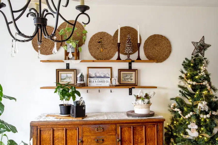 A dining room buffet hutch with shelves above decorated with Christmas decor.