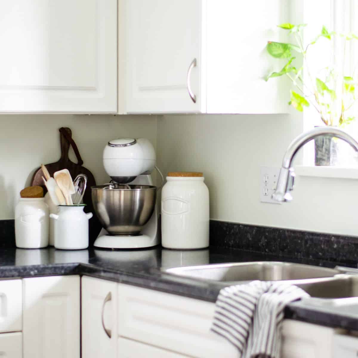 a kitchen counter corner with mixer and collection of pretty storage containers with utensils