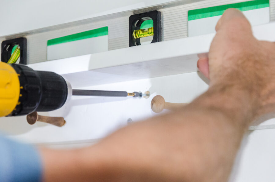 using a drill with a screwdriver attachment to hang a boho shelf on the wall