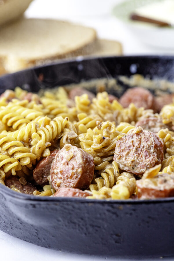 close up of farmer's sausage and noodles in a cast iron skillet