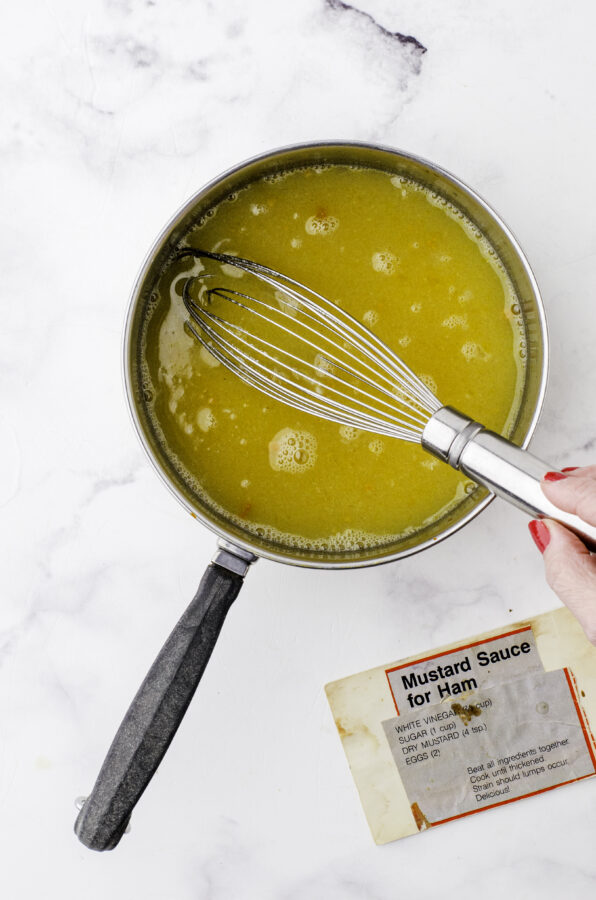 Ingredients for homemade mustard sauce for ham being whisked together in a saucepan.