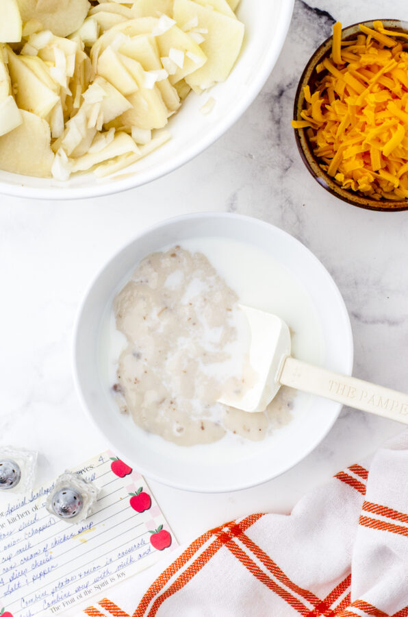 Mushroom soup and milk being mixed together in a bowl for scalloped potatoes recipe.