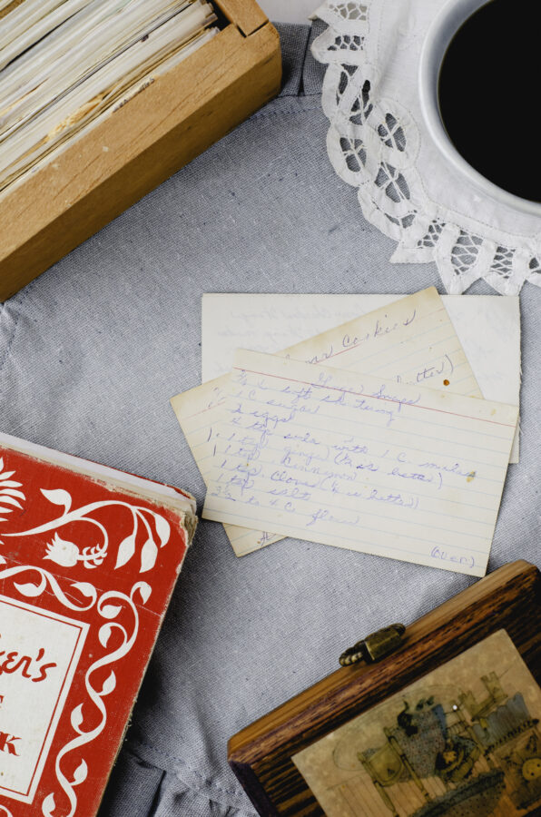 Handwritten recipe cards surrounded by vintage cookbooks