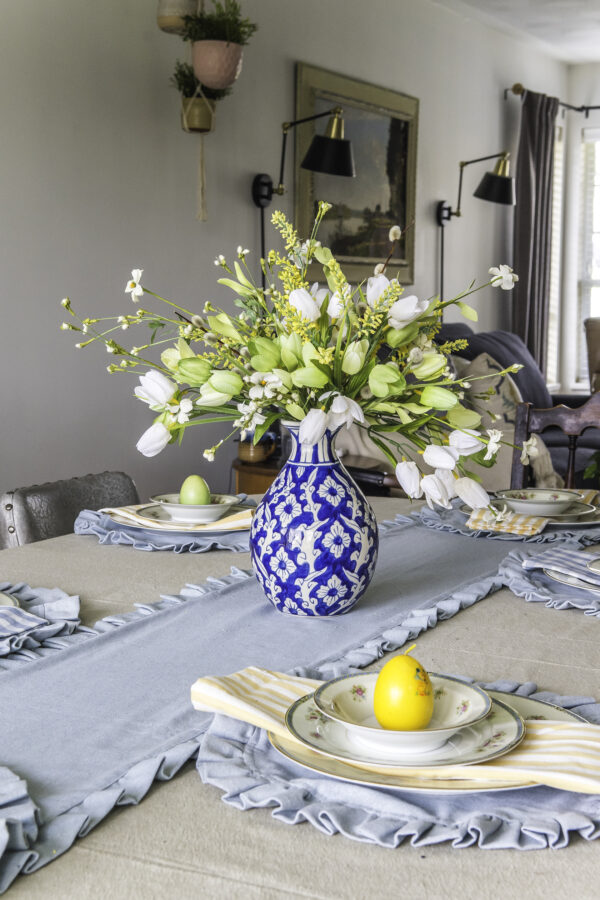 A ginger jar vase flower arrangment on a table that is set for Easter.