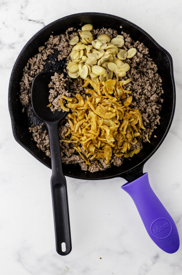 Browned hamburger with french fried onions and mushrooms being stirred in.