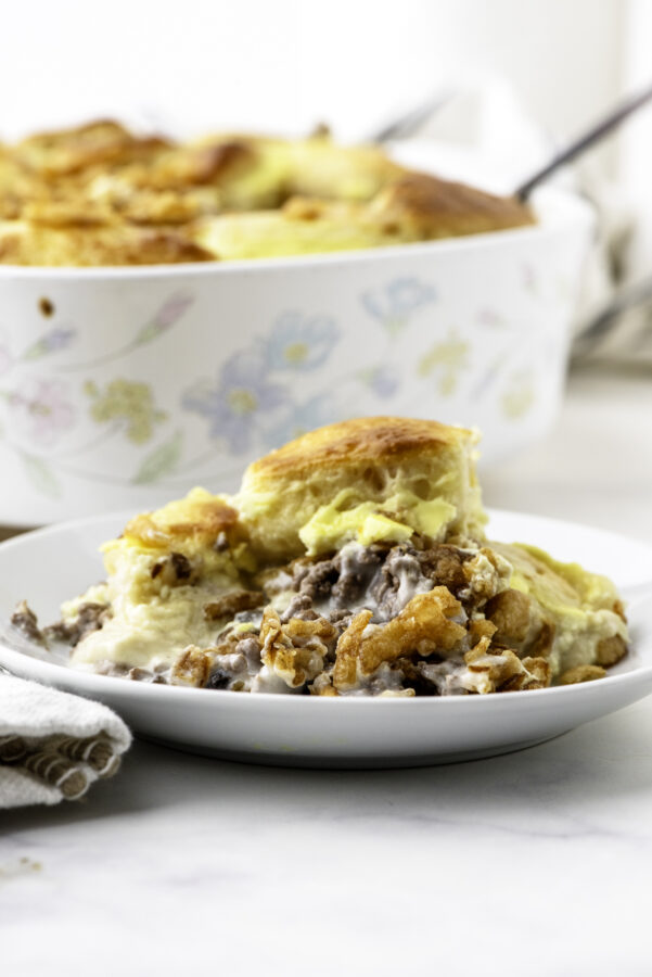 A plate with a serving of stroganaff hamburger casserole with canned biscuits and french fried onions.