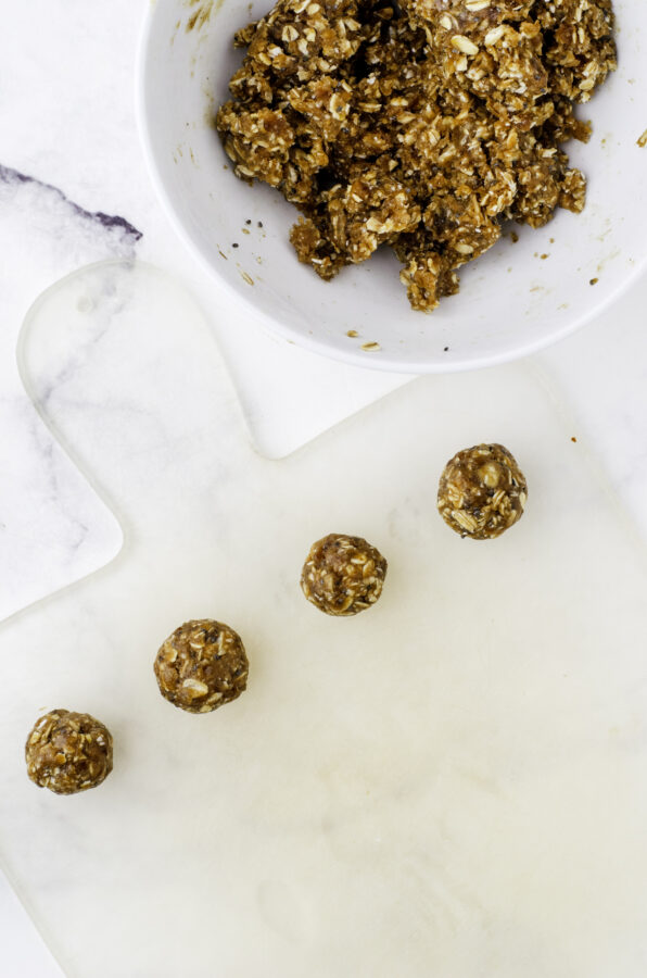 Date protein balls rolled into balls and lined up on a cutting board.