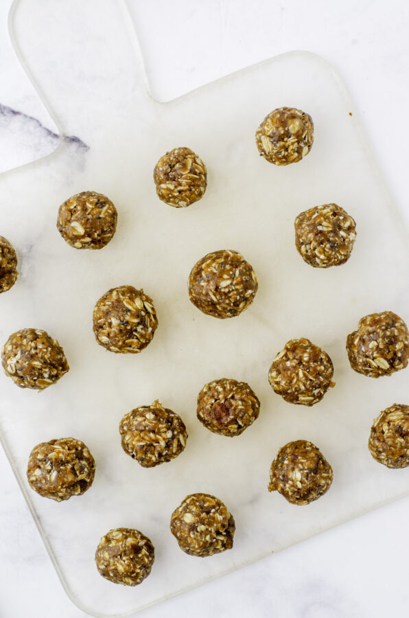 17 date balls lined up on a cutting board.