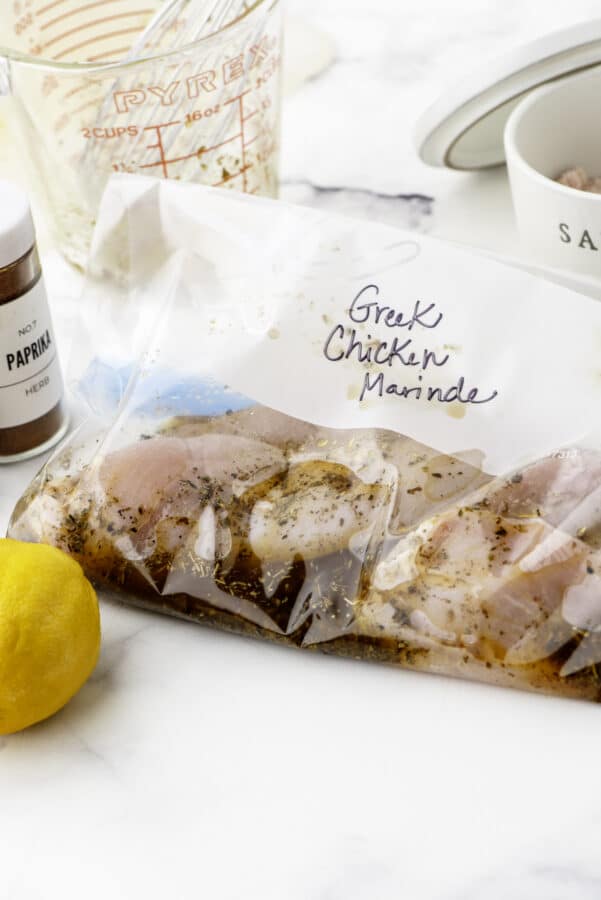 Greek chicken marinade recipe poured over chicken in a ziploc bag and marked with a sharpie marker on the front saying "Greek Chicken Marinade".