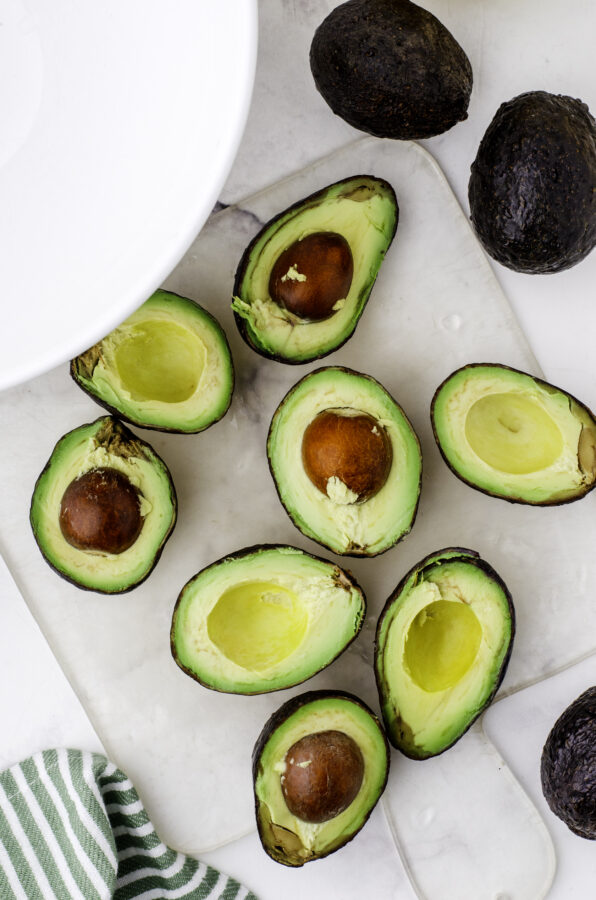 Avocados cut in half and sitting on a cutting board.