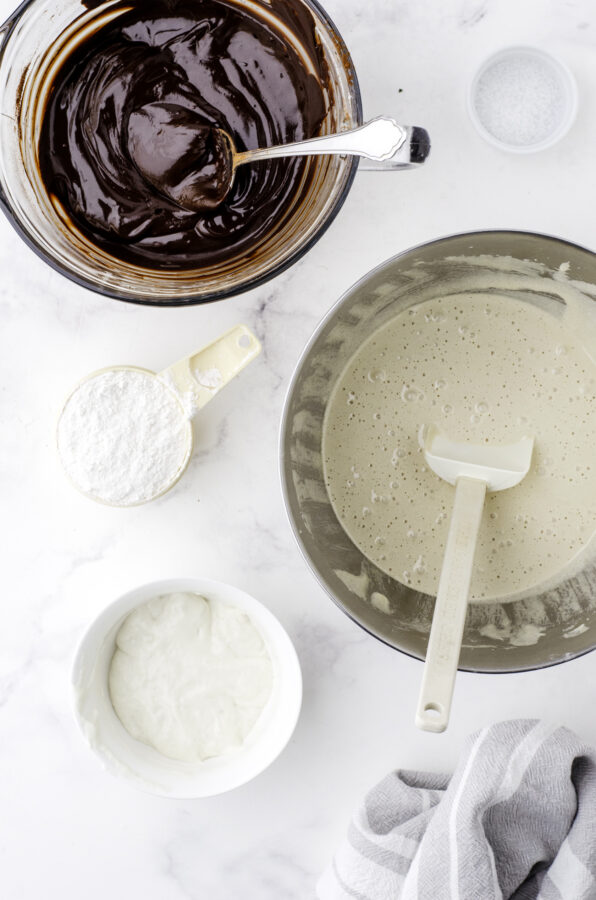 A microwave safe bowl with the chocolate mixture melted and stirred until smooth, and the bowl of a stand mixer with a mixture of beaten eggs and sugar.