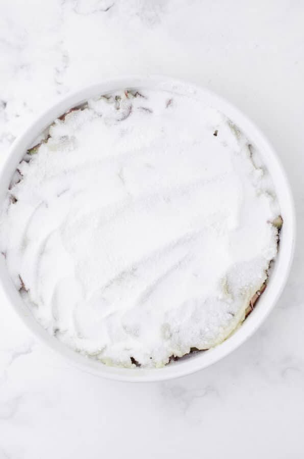 The powdered sugar and cornstarch mixture spread over the cake mixture for sticky rhubarb pudding that is baked in the oven