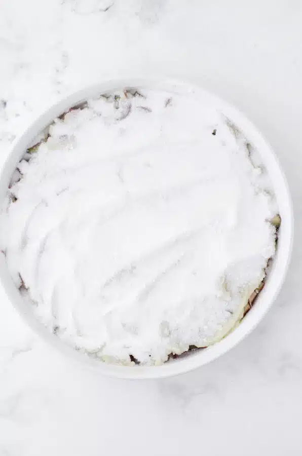 The powdered sugar and cornstarch mixture spread over the cake mixture for sticky rhubarb pudding that is baked in the oven