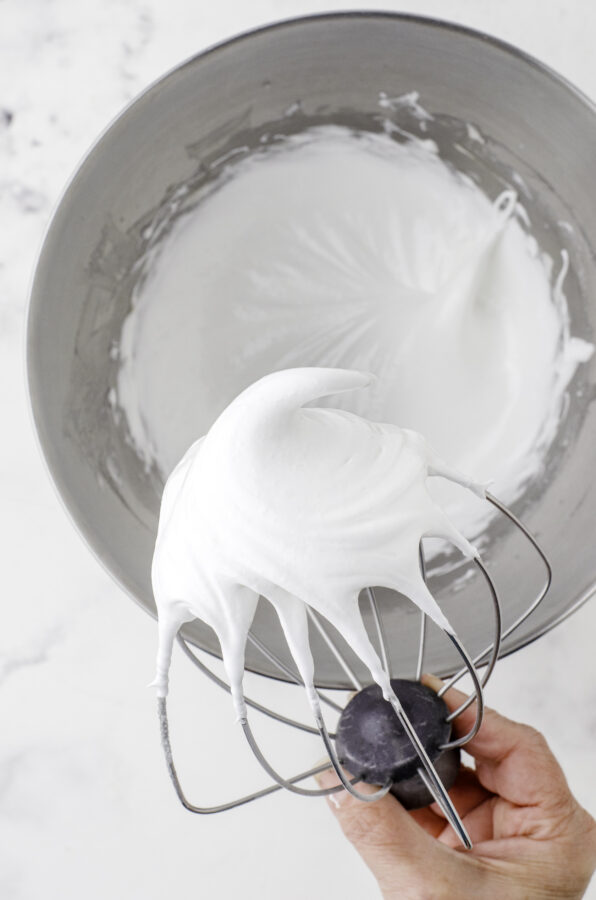 A whisk beater from a mixer with a peak of pavlova batter on the end.