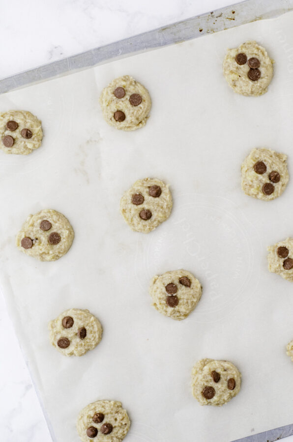 Banana Cookies dough scooped out and on a cookie sheet with chocolate chips in the top.