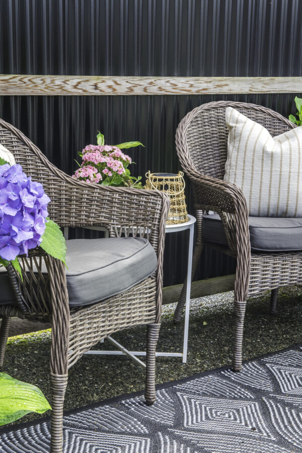 Two patio chairs with cushions with a side table between.