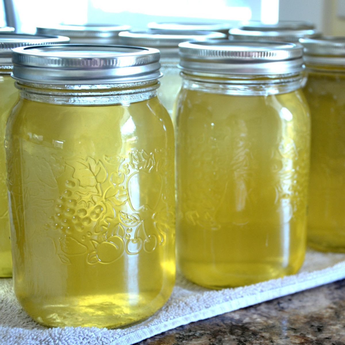 jars of homemade apple juice lined up on a counter