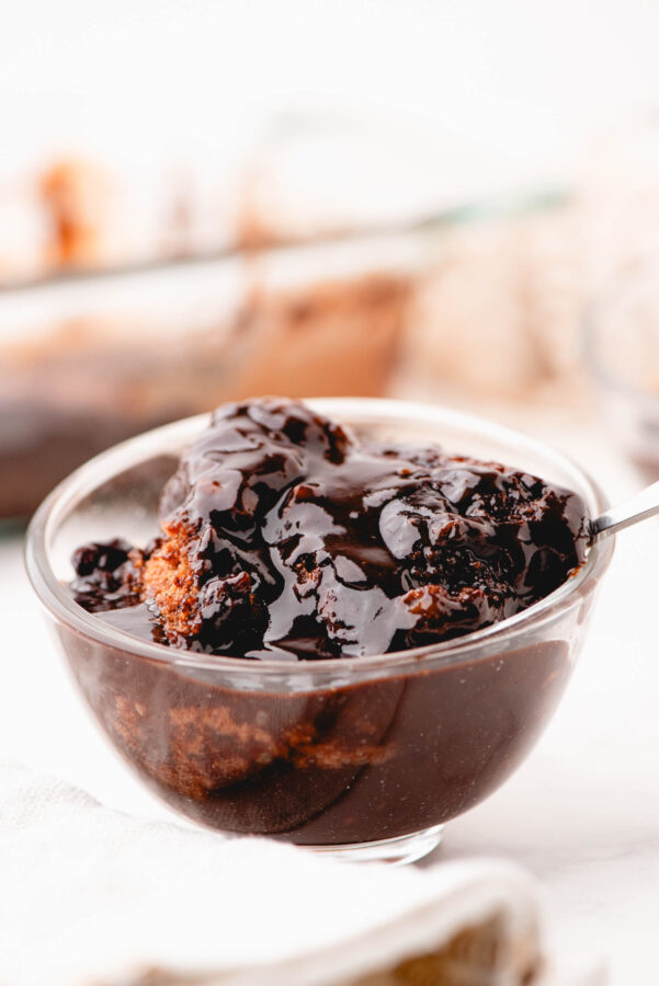 A bowl of chocolate pudding cake with a spoon in it.