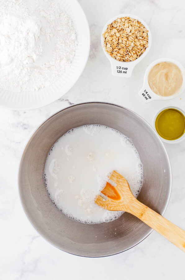 The white, milky liquid of the sourdough starter and water after it has been mixed together in the bowl of an electric mixer.