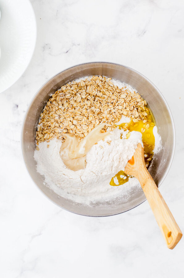 All the ingredients of honey oat sourdough bread in the bowl of an electric mixer before it is mixed together.