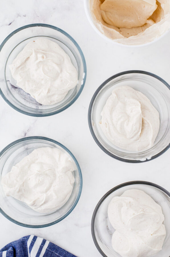 4 clear glass bowls with a serving of greek yogurt in each bowl.